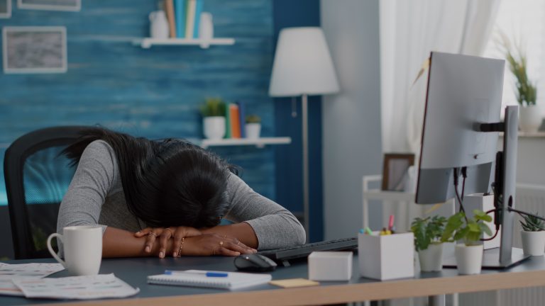 A woman with her face down on her desk tired and exhausted.