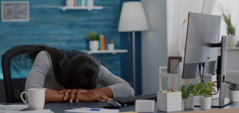 A woman with her face down on her desk tired and exhausted.
