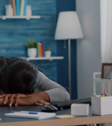 A woman with her face down on her desk tired and exhausted.