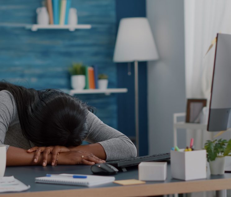 July Blog Post Header Image A woman with her face down on her desk tired and exhausted.