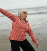 age-cymru-eVTv0dsBgt8-unsplash Elderly women stretching on the beach near water.